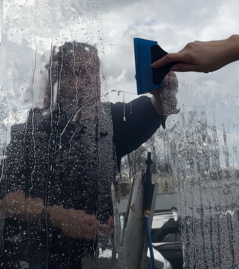 Frau bearbeitet Folie auf Fenster
