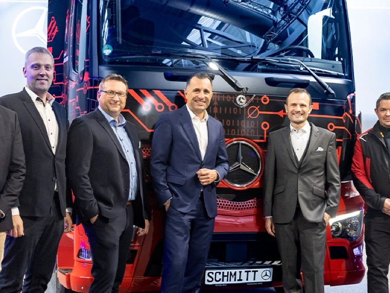 5 Männer in Anzügen vor LKW